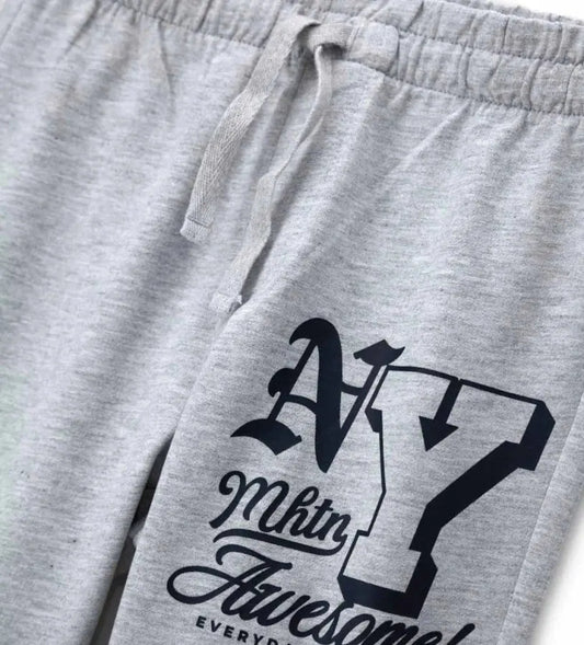 Λεπτομέρεια από το λάστιχο στους αστραγάλους και το τύπωμα στο γκρι παιδικό παντελόνι.