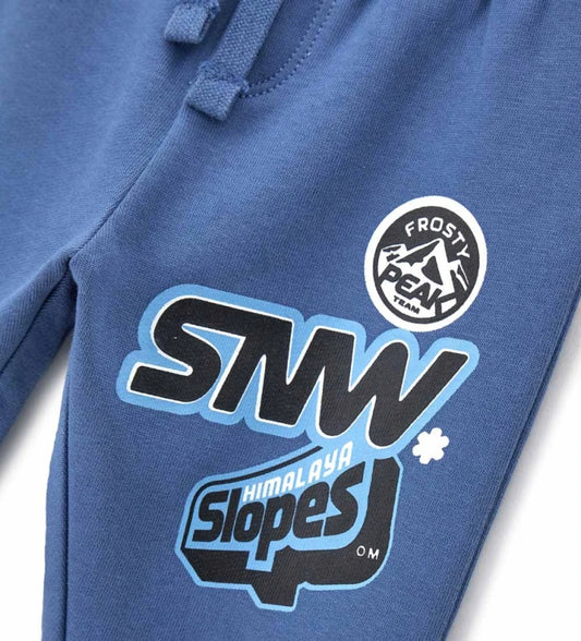 Μπλε παιδικό παντελόνι από ζεστό βαμβακερό fleece, ιδανικό για τον χειμώνα. Διαθέτει ελαστική μέση με ρυθμιζόμενο κορδόνι, λάστιχο στο τελείωμα και πλαϊνό τύπωμα. Άνετο και μοντέρνο, προσφέρει πρακτικότητα και στυλ στις καθημερινές εμφανίσεις των παιδιών.
