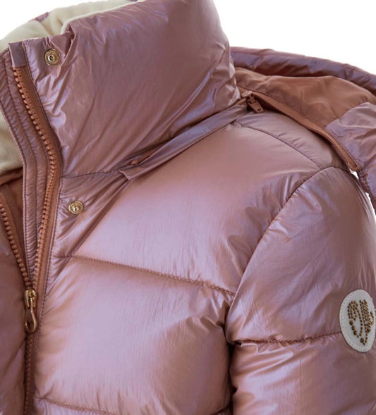 Καπιτονέ μπουφάν από γυαλιστερό νάιλον με αποσπώμενη κουκούλα και μακριά μανίκια με λάστιχο lycra για άνετη εφαρμογή. Διαθέτει κρυφά κουμπιά-σούστες, μονόχρωμο φερμουάρ, μπροστινές τσέπες και μεταλλικό λογότυπο με στρας για ένα κομψό και λειτουργικό look. Ιδανικό για στυλάτες χειμερινές εμφανίσεις με ζεστασιά και λάμψη.