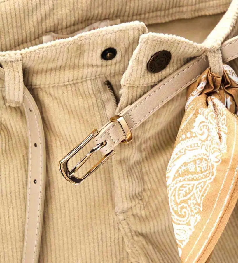 Παντελόνι καμπάνα από βελούδινο κοτλέ ύφασμα με ρυθμιζόμενη μέση, μπροστινό κλείσιμο με κουμπί, τσέπες μπροστά και πίσω και αποσπώμενη ζώνη με φουλάρι για μια μοντέρνα και ευέλικτη πινελιά.