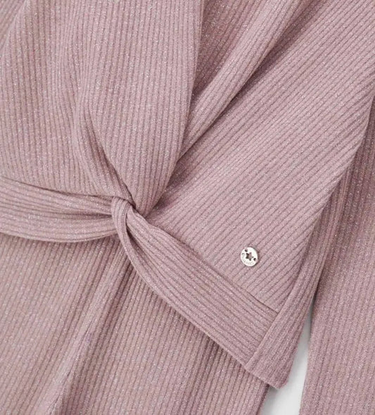 Σετ από ριπ ύφασμα με νήματα lurex που περιλαμβάνει μπλούζα με μακριά μανίκια και σταυρωτό μπροστινό σχέδιο, καθώς και παντελόνι καμπάνα με ελαστική μέση. Το μεταλλικό διακοσμητικό με λογότυπο ολοκληρώνει το look, προσθέτοντας μια κομψή και λαμπερή πινελιά. Ιδανικό για κοριτσίστικες εμφανίσεις με στυλ και άνεση.