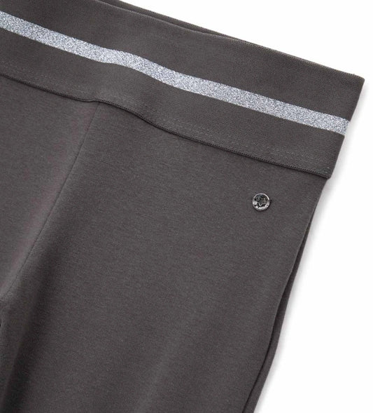 Κολάν καμπάνα από ελαστικό βαμβάκι με άνετη ελαστική μέση και λαμπερή lurex λωρίδα για μοντέρνο στυλ. Διακοσμημένο με μεταλλικό μενταγιόν στο πλάι, προσθέτει μια glam και κομψή πινελιά σε κάθε κοριτσίστικη εμφάνιση. Ιδανικό για casual αλλά και πιο στιλάτες περιστάσεις.