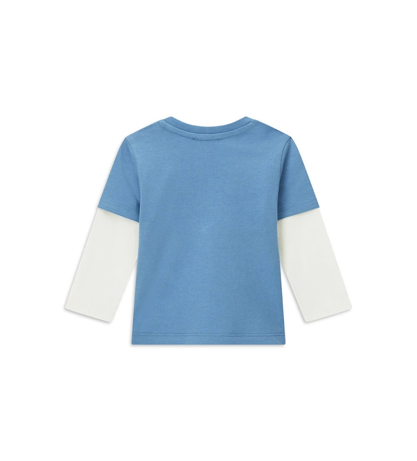 Βρεφική μπλούζα από βαμβάκι με διπλό μανίκι σε μπλε αντίθεση, στρογγυλή λαιμόκοψη με ριμπ τελείωμα και πρακτικό άνοιγμα στον ώμο με κουμπιά-σούστες. Διακοσμημένη με τύπωμα στο μπροστινό μέρος, προσφέρει άνεση και μοντέρνο στυλ για κάθε μέρα.