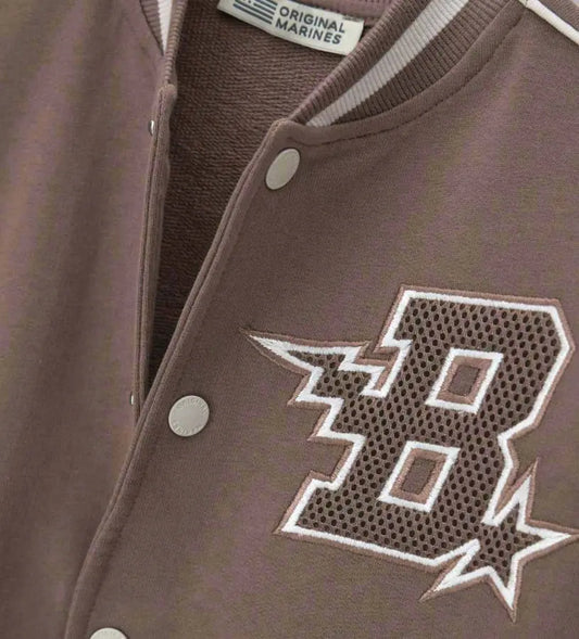 Λεπτομέρεια από το κεντημένο απλικέ και τα κουμπιά σούστες στο παιδικό varsity jacket.