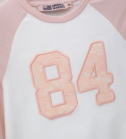 Λεπτομέρεια από το ανάγλυφο απλικέ δαντέλας στο στήθος της κοριτσίστικης μπλούζας.