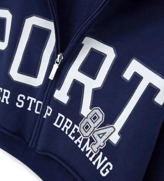 Λεπτομέρεια από το φερμουάρ και το γκλίτερ τύπωμα 84 στην παιδική ζακέτα.