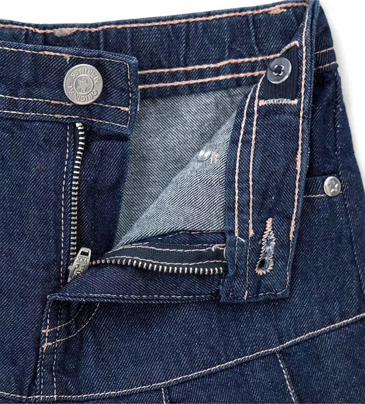 Λεπτομέρεια από το κλείσιμο με κουμπί και τις πιέτες στο μπροστινό μέρος του denim culotte.