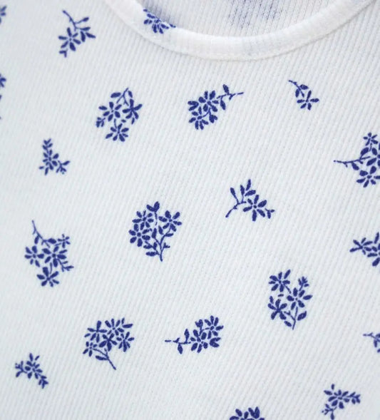 Κοντινό πλάνο στην ανάγλυφη ριμπ ύφανση (costina) και το floral σχέδιο της βρεφικής μπλούζας.