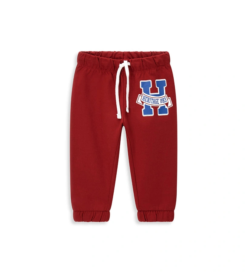 Παιδικό παντελόνι σε κόκκινο χρώμα από ελαστικό βαμβακερό fleece, ιδανικό για καθημερινή άνεση. Διαθέτει ρυθμιζόμενη μέση με κορδόνι και διακριτικό τύπωμα στο μπροστινό μέρος. Ένα πρακτικό και μοντέρνο κομμάτι, ιδανικό για casual παιδικές εμφανίσεις.
