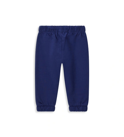 Παιδικό παντελόνι σε μπλε χρώμα από ελαστικό βαμβακερό fleece, ιδανικό για καθημερινή άνεση. Διαθέτει ρυθμιζόμενη μέση με κορδόνι και διακριτικό τύπωμα στο μπροστινό μέρος. Ένα πρακτικό και μοντέρνο κομμάτι για κάθε παιδική εμφάνιση.