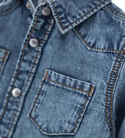 Λεπτομέρεια από το ελαφρύ βαμβακερό ύφασμα και το κλείσιμο στο παιδικό τζιν πουκάμισο.