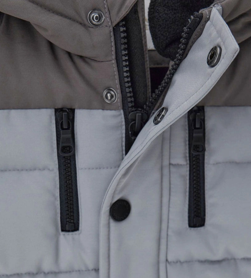 Παιδικό παρκά με κουκούλα από καπιτονέ και επενδυμένο νάιλον, με εσωτερικές λεπτομέρειες από ζεστή οικολογική γούνα για περισσότερη άνεση. Διαθέτει άνοιγμα με φερμουάρ και κουμπιά-σούστες, διακοσμητικές τσέπες με φερμουάρ και ριμπ μανσέτες. Ένα κομψό και πρακτικό μπουφάν, ιδανικό για τις κρύες χειμερινές μέρες.