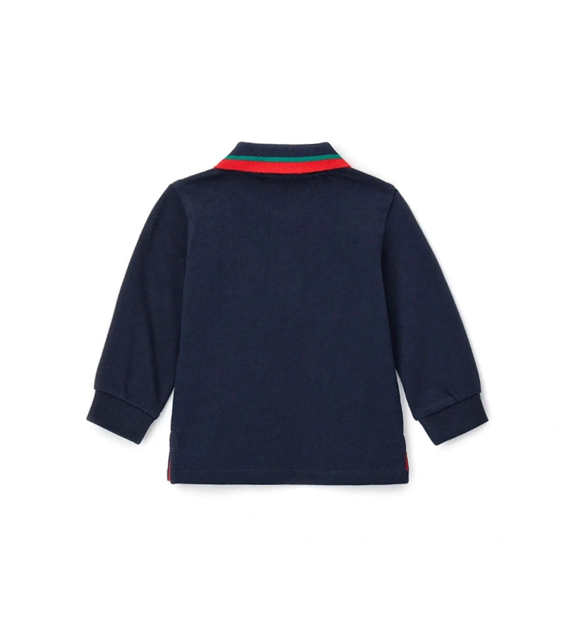 Βαμβακερή μπλούζα πόλο, απαλή και άνετη, με μακριά μανίκια και γιακά σε ριπ ύφανση από νήμα βαφής. Διαθέτει μπροστινό άνοιγμα με κουμπιά, πλαϊνά ανοίγματα, ριμπ τελειώματα και διακοσμητικό απλικέ στο μπροστινό μέρος.