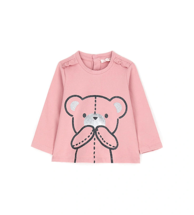 Μπλούζα από ελαστικό βαμβάκι με στρογγυλή λαιμόκοψη, μακριά μανίκια, βολάν στους ώμους και τύπωμα με γκλίτερ και μεταλλικές λεπτομέρειες στο μπροστινό μέρος. Για τα μεγέθη έως 2–3 ετών διαθέτει πρακτικό άνοιγμα με κουμπιά.