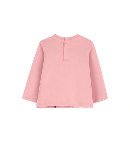 Μπλούζα από ελαστικό βαμβάκι με στρογγυλή λαιμόκοψη, μακριά μανίκια, βολάν στους ώμους και τύπωμα με γκλίτερ και μεταλλικές λεπτομέρειες στο μπροστινό μέρος. Για τα μεγέθη έως 2–3 ετών διαθέτει πρακτικό άνοιγμα με κουμπιά.