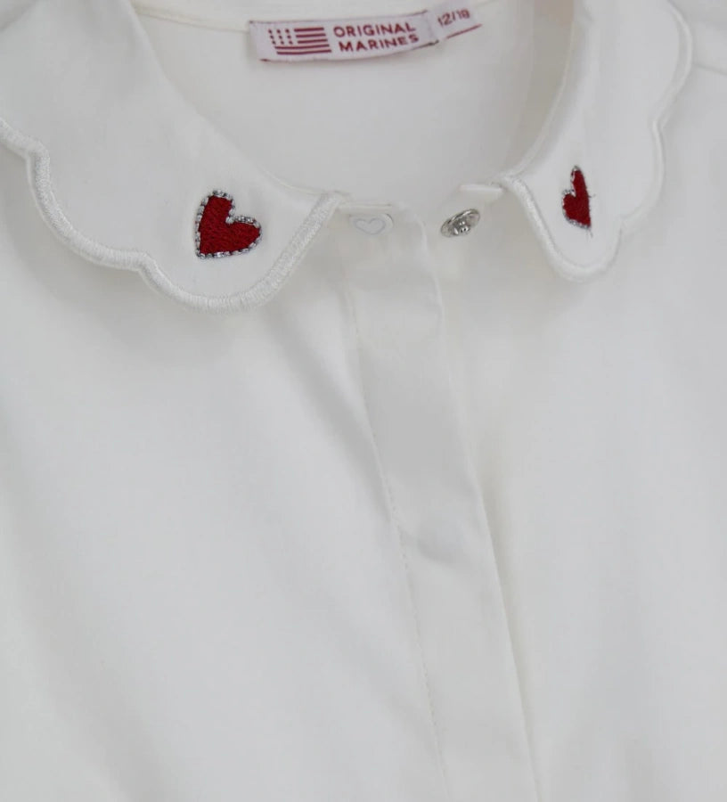 Παιδικό κορμάκι-πουκάμισο από βαμβακερό ποπλίνα με κόψιμο στη μέση και κάτω μέρος από βαμβακερό jersey για άνετη εφαρμογή. Διαθέτει γιακά με κέντημα καρδιάς, μπροστινό άνοιγμα με κουμπιά και κουμπιά στο εσωτερικό του καβάλου και στις μανσέτες. Ένα κομψό και πρακτικό κομμάτι, ιδανικό για ιδιαίτερες εμφανίσεις με στυλ.