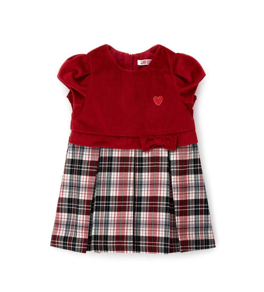 Φόρεμα δύο υφών με βελούδινο επάνω μέρος, κοντά φουσκωτά μανίκια και καρό κάτω μέρος με βαμβακερή φόδρα. Διαθέτει φιόγκο στη μέση, κέντημα στην πλευρά της καρδιάς και κρυφό φερμουάρ στο πίσω μέρος.