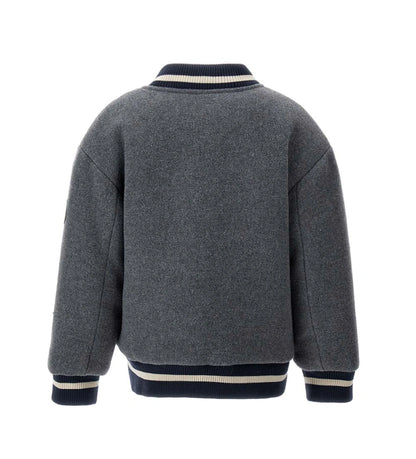 Παιδικό μπουφάν bomber από ύφασμα τύπου μάλλινο με μπροστινές τσέπες και καπιτονέ, επενδυμένη εσωτερική φόδρα για επιπλέον άνεση. Διαθέτει άνοιγμα με κουμπιά-σούστες και ριμπ τελειώματα σε χρώμα βαφής. Ένα ζεστό και μοντέρνο κομμάτι, ιδανικό για στιλάτες χειμερινές εμφανίσεις.