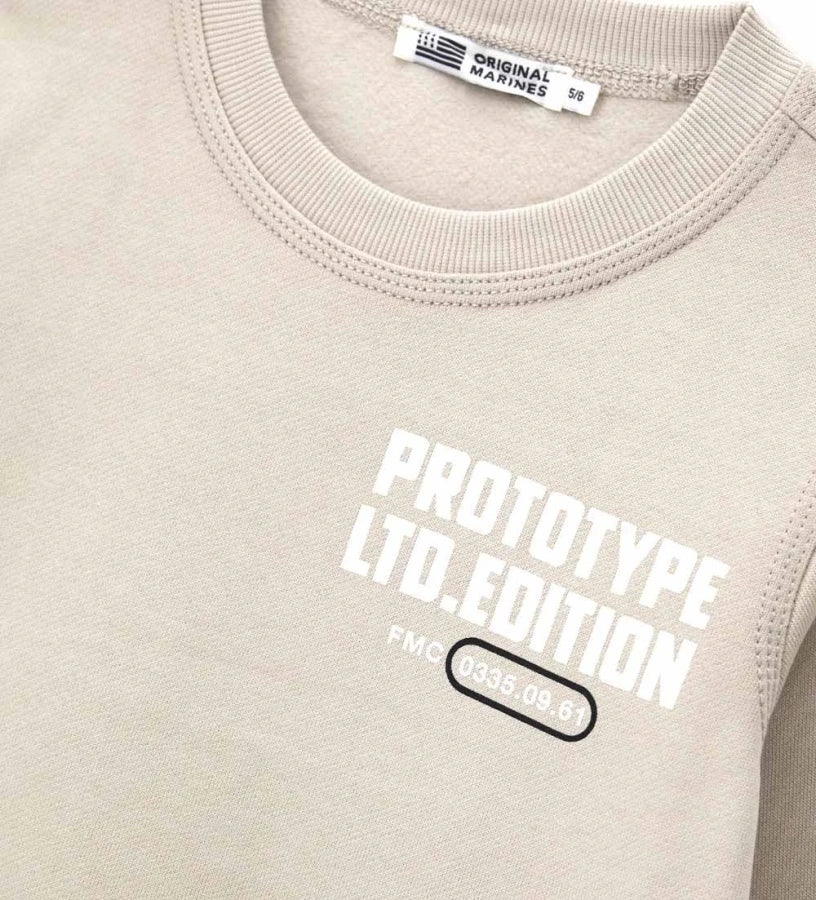 Μπεζ παιδικό φούτερ από βαμβάκι με στρογγυλή λαιμόκοψη και ριμπ τελειώματα. Διακοσμημένο με γραφικό τύπωμα στο μπροστινό και πίσω μέρος, διακοσμητική τομή στην πλάτη και πλαϊνή ετικέτα. Ένα μοντέρνο και άνετο κομμάτι, ιδανικό για casual εμφανίσεις με στυλ.