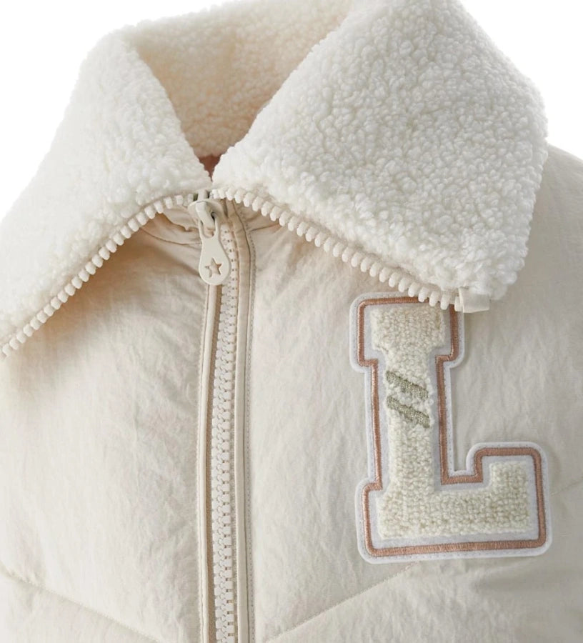 Μπουφάν από καπιτονέ και αφρώδες νάιλον με γιακά από οικολογική γούνα και μακριά μανίκια. Διαθέτει φόδρα από νάιλον, φερμουάρ σε μονόχρωμο τόνο, μπροστινές τσέπες και κεντημένο σήμα για ένα ζεστό, κομψό και μοντέρνο στυλ, ιδανικό για τις κρύες μέρες του χειμώνα.