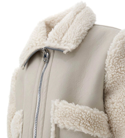 Κοντό μπουφάν από ψεύτικο shearling με ψηλό γιακά και μακριά μανίκια. Διαθέτει μπροστινές τσέπες και άνοιγμα με φερμουάρ, για μοντέρνα, ζεστή και πρακτική εμφάνιση.