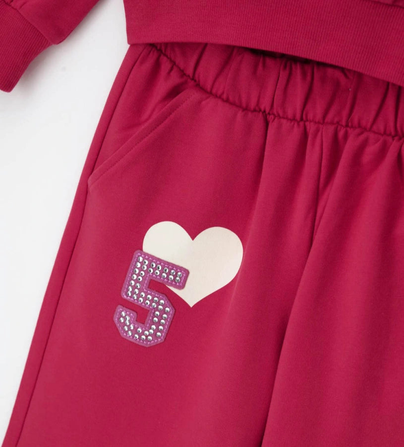 Σετ φόρμας από ελαστικό βαμβάκι, που αποτελείται από φούτερ με στρογγυλή λαιμόκοψη, μακριά μανίκια, τύπωμα και ριμπ τελειώματα. Παντελόνι με ελαστική μέση, τσέπες και τύπωμα μπροστά. Και τα δύο κομμάτια είναι διακοσμημένα με απλικέ και τυπώματα για ένα μοντέρνο στυλ.