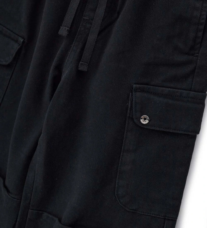 Παιδικό baggy παντελόνι από βαμβακερό twill με κορδόνι και ελαστική μέση και τελείωμα για άνετη εφαρμογή. Διαθέτει μπροστινές τσέπες με ρέλι, πλαϊνές τσέπες και μεταλλικό διακοσμητικό με λογότυπο για μια κομψή πινελιά. Ιδανικό για μοντέρνες και άνετες casual εμφανίσεις.