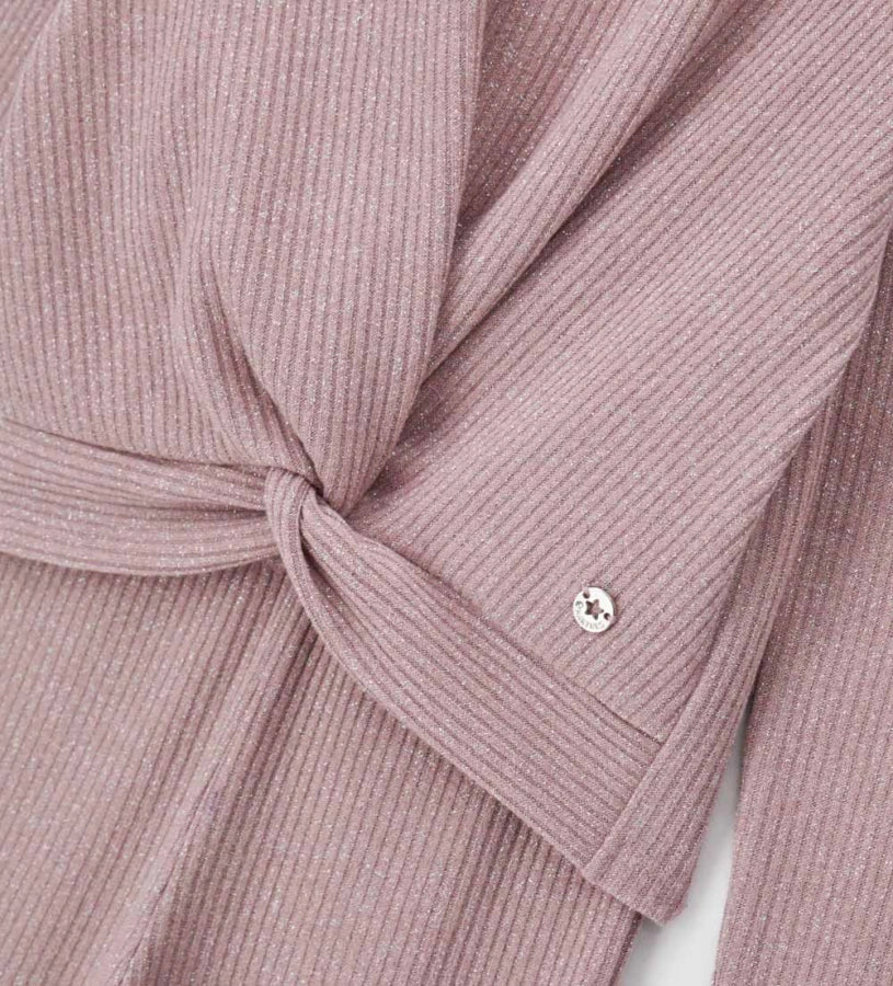 Σετ από ριπ ύφασμα με νήματα lurex που περιλαμβάνει μπλούζα με μακριά μανίκια και σταυρωτό μπροστινό σχέδιο, καθώς και παντελόνι καμπάνα με ελαστική μέση. Το μεταλλικό διακοσμητικό με λογότυπο ολοκληρώνει το look, προσθέτοντας μια κομψή και λαμπερή πινελιά. Ιδανικό για κοριτσίστικες εμφανίσεις με στυλ και άνεση.