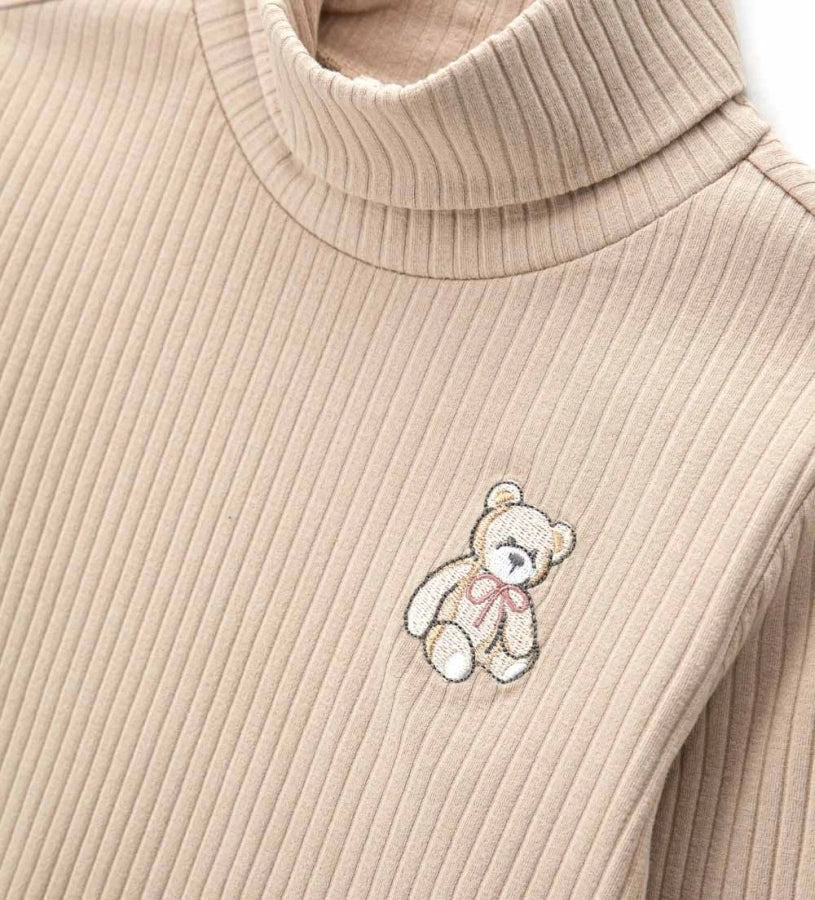 Πλεκτό ριπ ζιβάγκο με γυριστό γιακά και μακριά μανίκια, διακοσμημένο με χαριτωμένο κέντημα αρκουδάκι στο μπροστινό μέρος. Απαλό, ζεστό και ιδανικό για γλυκές και μοντέρνες εμφανίσεις.