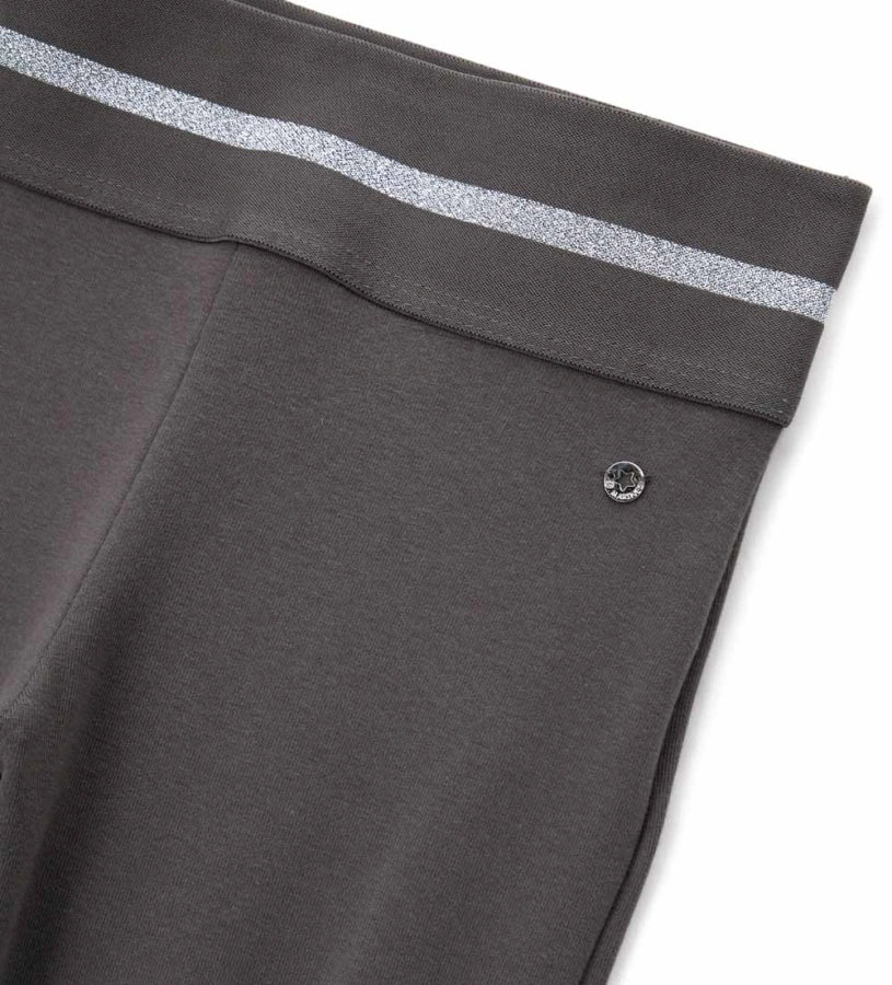 Κολάν καμπάνα από ελαστικό βαμβάκι με άνετη ελαστική μέση και λαμπερή lurex λωρίδα για μοντέρνο στυλ. Διακοσμημένο με μεταλλικό μενταγιόν στο πλάι, προσθέτει μια glam και κομψή πινελιά σε κάθε κοριτσίστικη εμφάνιση. Ιδανικό για casual αλλά και πιο στιλάτες περιστάσεις.