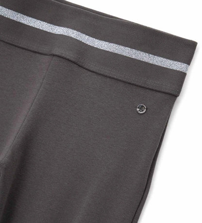 Κολάν καμπάνα από ελαστικό βαμβάκι με άνετη ελαστική μέση και λαμπερή lurex λωρίδα για μοντέρνο στυλ. Διακοσμημένο με μεταλλικό μενταγιόν στο πλάι, προσθέτει μια glam και κομψή πινελιά σε κάθε κοριτσίστικη εμφάνιση. Ιδανικό για casual αλλά και πιο στιλάτες περιστάσεις.