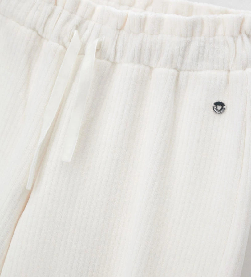 Παντελόνι από βελουτέ ύφασμα (κορδέλα) με ελαστική μέση και κορδόνι για τέλεια εφαρμογή. Διακοσμημένο με μεταλλικά ασημί διακοσμητικά με λογότυπο, αποτελεί ιδανική επιλογή για κάθε περίσταση, συνδυάζοντας άνεση και κομψό στυλ.