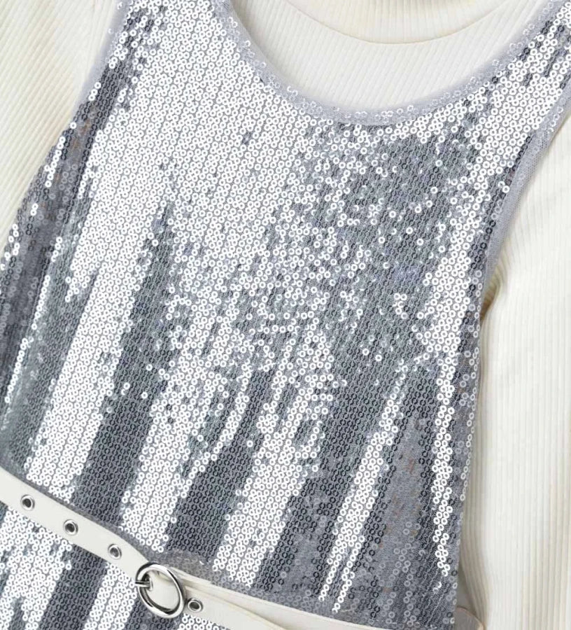 Σετ που αποτελείται από αμάνικο φόρεμα από ύφασμα με παγιέτες, με εσωτερική φόδρα, στρογγυλή λαιμόκοψη και άνοιγμα στο πίσω μέρος, καθώς και ζιβάγκο τοπ με μακριά ριπ μανίκια, για κομψή και λαμπερή εμφάνιση.