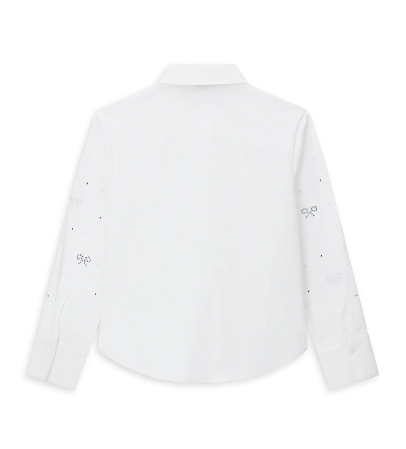 Παιδικό πουκάμισο από βαμβάκι με κουμπιά στο μπροστινό μέρος, μακριά μανίκια και μανσέτες με κουμπί. Διαθέτει αφαιρούμενο φιόγκο από λαμιναρισμένο ύφασμα και στρας στο μπροστινό μέρος και στα μανίκια για ένα λαμπερό και μοντέρνο στυλ.