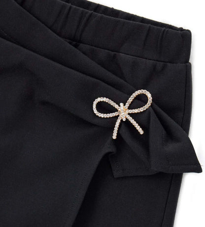 Παντελόνι-φούστα σε πλεκτό ύφασμα Milano με ελαστική μέση, draping λεπτομέρειες και κόμπο στο μπροστινό μέρος. Με μεταλλική αγκράφα για μια κομψή και μοντέρνα πινελιά, ιδανικό για ένα κομψό και στιλάτο look.