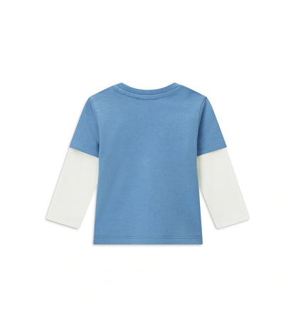 Βρεφική μπλούζα από βαμβάκι με διπλό μανίκι σε μπλε αντίθεση, στρογγυλή λαιμόκοψη με ριμπ τελείωμα και πρακτικό άνοιγμα στον ώμο με κουμπιά-σούστες. Διακοσμημένη με τύπωμα στο μπροστινό μέρος, προσφέρει άνεση και μοντέρνο στυλ για κάθε μέρα.