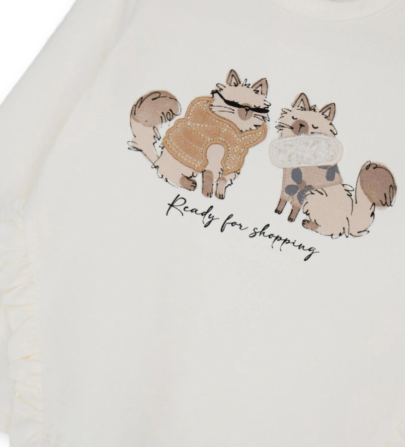 Βαμβακερή μπλούζα με στρογγυλή λαιμόκοψη και μακριά μανίκια. Διαθέτει πρακτικό άνοιγμα με κουμπιά-σούστες στο πίσω μέρος και είναι διακοσμημένη με βολάν, τύπωμα και κέντημα στο μπροστινό μέρος, για μοντέρνα και απαλή εμφάνιση.