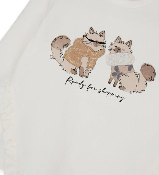 Βαμβακερή μπλούζα με στρογγυλή λαιμόκοψη και μακριά μανίκια. Διαθέτει πρακτικό άνοιγμα με κουμπιά-σούστες στο πίσω μέρος και είναι διακοσμημένη με βολάν, τύπωμα και κέντημα στο μπροστινό μέρος, για μοντέρνα και απαλή εμφάνιση.