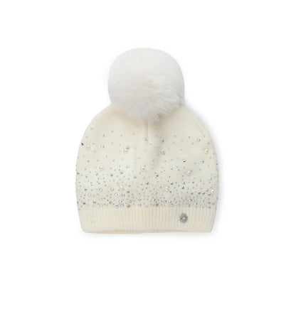 Πλεκτό σκουφάκι διακοσμημένο με στρας, τρουκς και πέρλες, ολοκληρωμένο με φουντάκι από οικολογική γούνα. Ένα ζεστό και κομψό αξεσουάρ που συνδυάζει στυλ και άνεση, χαρίζοντας μια πινελιά κλάσης στις χειμερινές εμφανίσεις.