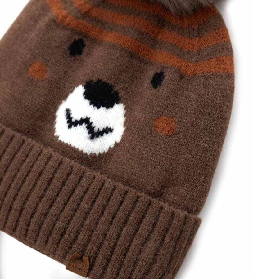 Σκουφάκι με καλύμματα για τα αυτιά, κορδόνια, jacquard σχέδιο ρύγχους και φουντάκι — διασκεδαστικό και πρακτικό για τις κρύες μέρες.