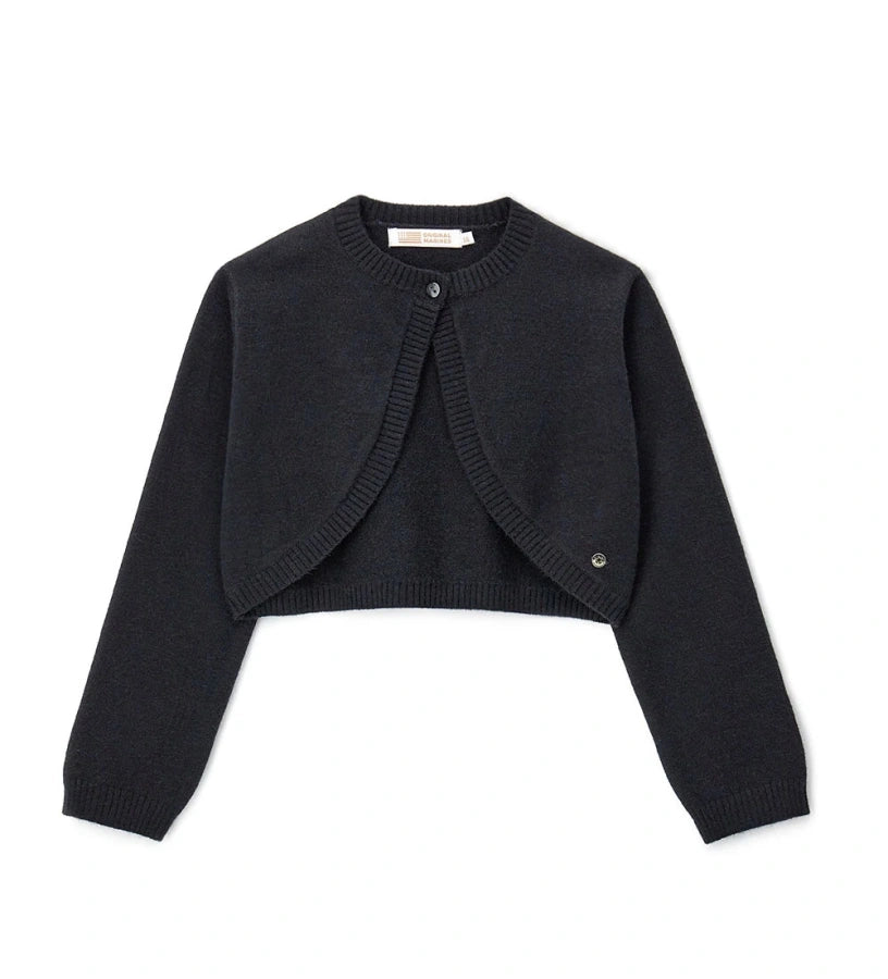 Πλεκτό μπολερό από μείγμα μαλλιού με στρογγυλή λαιμόκοψη, άνοιγμα με κουμπί και ριμπ τελειώματα σε λαιμό και μανσέτες. Ένα κομψό και εκλεπτυσμένο ρούχο, διακοσμημένο με μεταλλικό μενταγιόν.