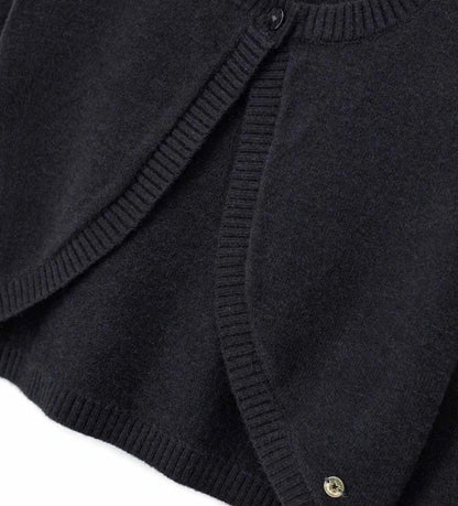 Πλεκτό μπολερό από μείγμα μαλλιού με στρογγυλή λαιμόκοψη, άνοιγμα με κουμπί και ριμπ τελειώματα σε λαιμό και μανσέτες. Ένα κομψό και εκλεπτυσμένο ρούχο, διακοσμημένο με μεταλλικό μενταγιόν.