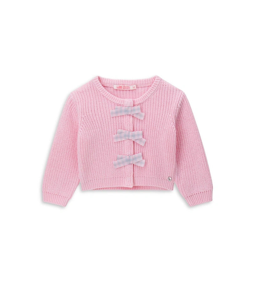 Παιδική ζακέτα από βαμβακερό νήμα με στρογγυλή λαιμόκοψη, ριμπ τελειώματα και μακριά μανίκια. Διαθέτει μπροστινό άνοιγμα με κρυφά κουμπιά-σούστες, διακοσμητικούς φιόγκους από καρό ύφασμα και μενταγιόν στο μπροστινό μέρος. Ένα εκλεπτυσμένο και απαλό κομμάτι, ιδανικό για κοριτσίστικες εμφανίσεις με ρομαντικό στυλ.