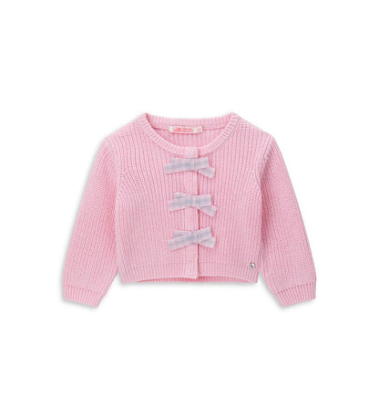 Παιδική ζακέτα από βαμβακερό νήμα με στρογγυλή λαιμόκοψη, ριμπ τελειώματα και μακριά μανίκια. Διαθέτει μπροστινό άνοιγμα με κρυφά κουμπιά-σούστες, διακοσμητικούς φιόγκους από καρό ύφασμα και μενταγιόν στο μπροστινό μέρος. Ένα εκλεπτυσμένο και απαλό κομμάτι, ιδανικό για κοριτσίστικες εμφανίσεις με ρομαντικό στυλ.