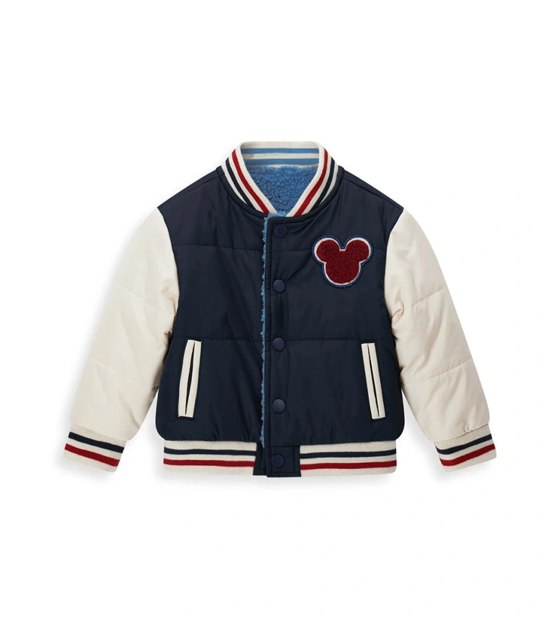 Αναστρέψιμο μπουφάν bomber Disney Mickey Mouse με γέμισμα. Η μία πλευρά από νάιλον με μανίκια σε αντίθεση και μπροστινό απλικέ, και η δεύτερη πλευρά από ζεστό οικολογικό teddy με μανίκια σε αντίθεση και απλικέ. Κλείσιμο με κουμπιά-σούστες και ριμπ τελειώματα από βαμμένο νήμα για ένα δυναμικό και ζεστό στυλ.