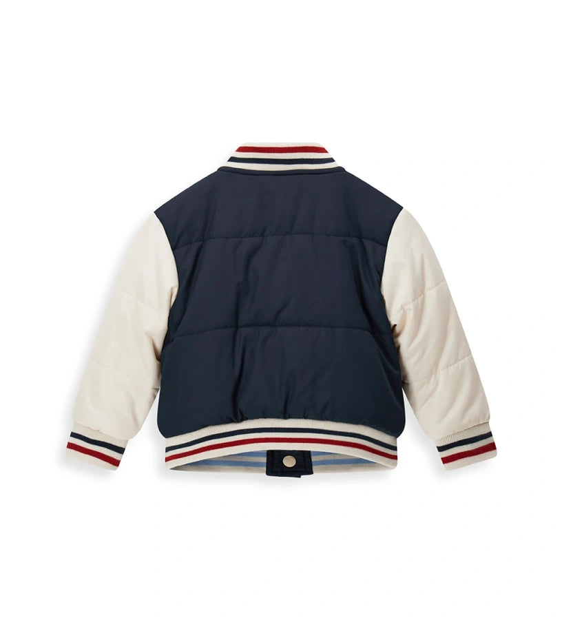 Αναστρέψιμο μπουφάν bomber Disney Mickey Mouse με γέμισμα. Η μία πλευρά από νάιλον με μανίκια σε αντίθεση και μπροστινό απλικέ, και η δεύτερη πλευρά από ζεστό οικολογικό teddy με μανίκια σε αντίθεση και απλικέ. Κλείσιμο με κουμπιά-σούστες και ριμπ τελειώματα από βαμμένο νήμα για ένα δυναμικό και ζεστό στυλ.