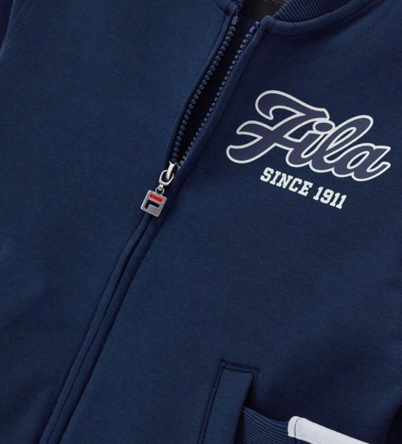 Σετ φόρμας Fila από τεχνικό ύφασμα, με μπλούζα μακρυμάνικη που διαθέτει κρυφό φερμουάρ, τύπωμα στο μπροστινό μέρος και ριμπ τελειώματα, και παντελόνι με ρυθμιζόμενο κορδόνι στη μέση, τυπωμένο λογότυπο και κεντημένη ετικέτα στο πλάι.