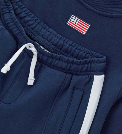 Σετ φόρμας Fila από τεχνικό ύφασμα, με μπλούζα μακρυμάνικη που διαθέτει κρυφό φερμουάρ, τύπωμα στο μπροστινό μέρος και ριμπ τελειώματα, και παντελόνι με ρυθμιζόμενο κορδόνι στη μέση, τυπωμένο λογότυπο και κεντημένη ετικέτα στο πλάι.