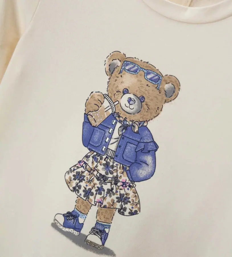 Κοντινό πλάνο στα strass και το glitter που διακοσμούν το αρκουδάκι στην παιδική μπλούζα.