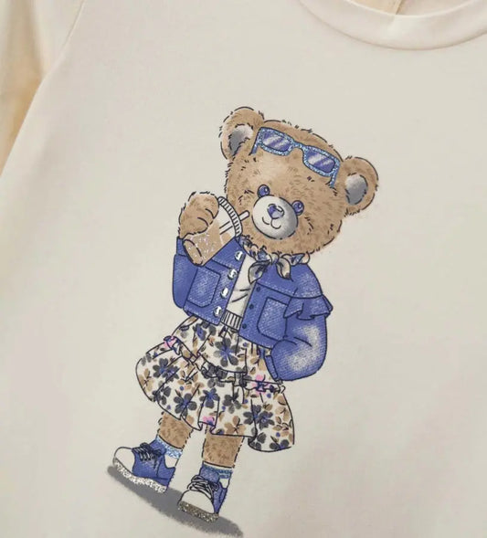Κοντινό πλάνο στα strass και το glitter που διακοσμούν το αρκουδάκι στην παιδική μπλούζα.